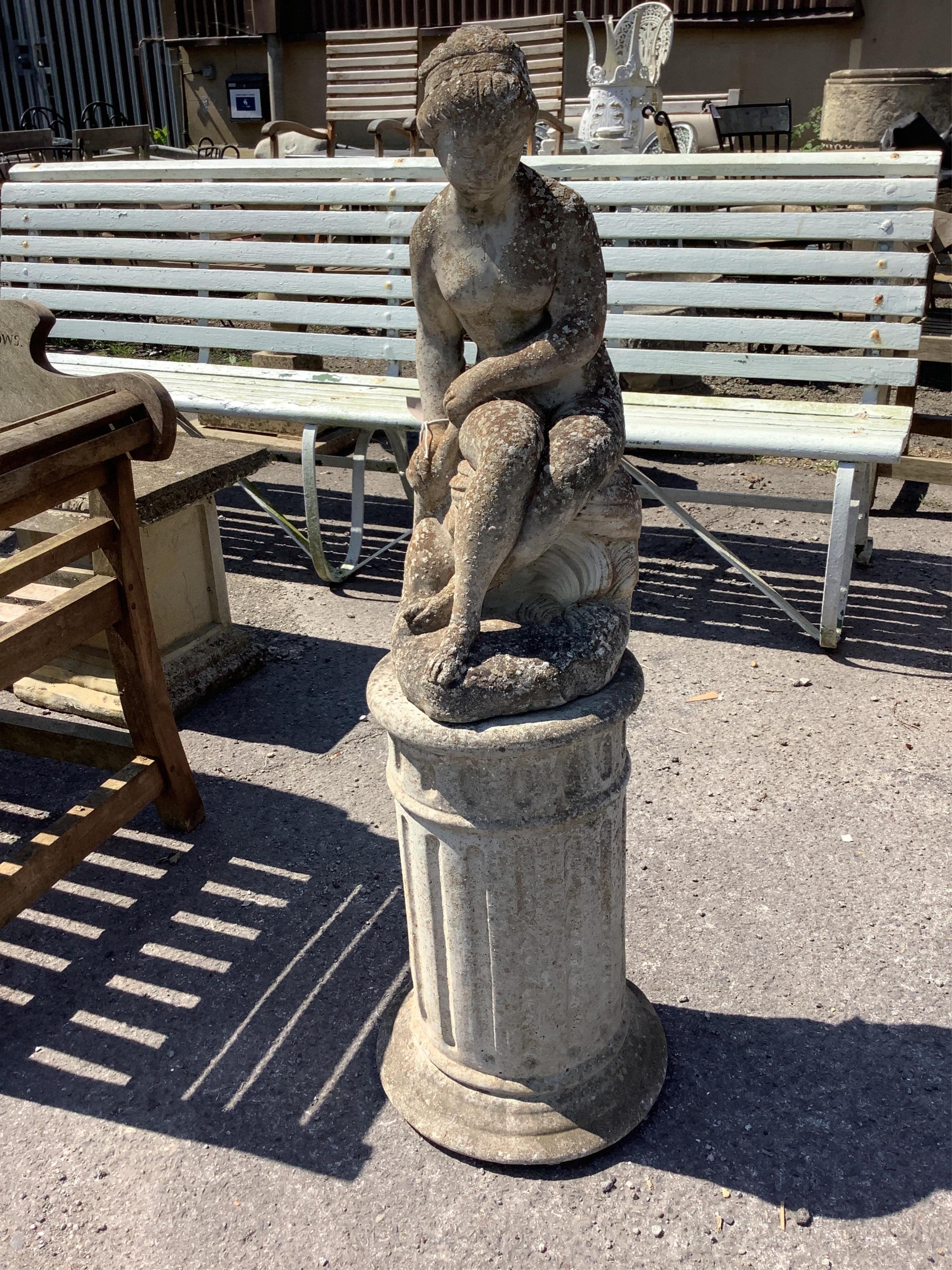 A reconstituted stone seated lady garden statue on circular plinth, height 110cm